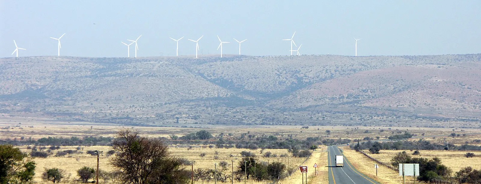 Wind turbines along a ridgeline at the Cookhouse wind farm in the Eastern Cape, with a road running through the valley below.